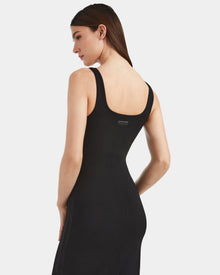 A woman with straight brown hair models contemporary elegance in the Rudsak WANDA - 8524035 Black, a fitted sleeveless black dress in stretch performance fabric, shown from the back and side against a plain white background.