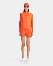 A woman wearing the Rudsak LOUISE - 8124046 Orange Sorbet womens hybrid knit sweater jacket.