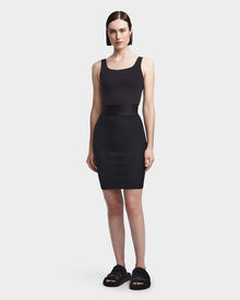 A woman with straight dark hair faces forward in a sleeveless black tank top, the Rudsak CHEYNA - 8523514 Black womens pencil skirt, and black slide sandals, against a plain white background.
