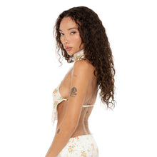 Side profile of model highlighting the Kiku Top‚Äôs open side and halter neck design with delicate floral print. **ivory