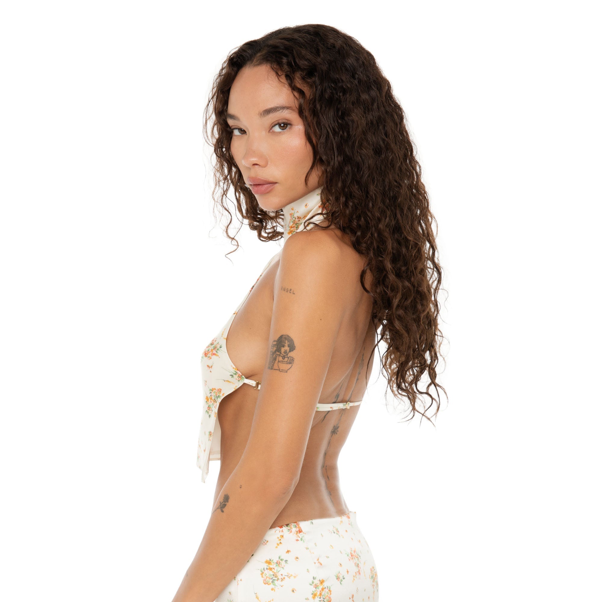 Side profile of model highlighting the Kiku Top‚Äôs open side and halter neck design with delicate floral print. **ivory
