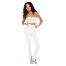 Model styling Kylu Pants in white with a bandeau top, holding waistband to show high-rise fit. **white